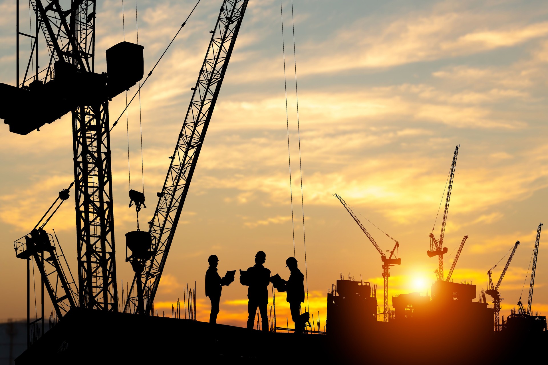 Silhouette of Engineer and worker team on building site, construction site at sunset in evening time Silhouette of Engineer and worker team on building site, construction site at sunset in evening time